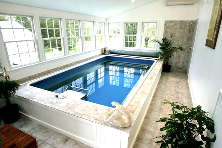 Indoor swimming pool surrounded by large windows and modern decor.